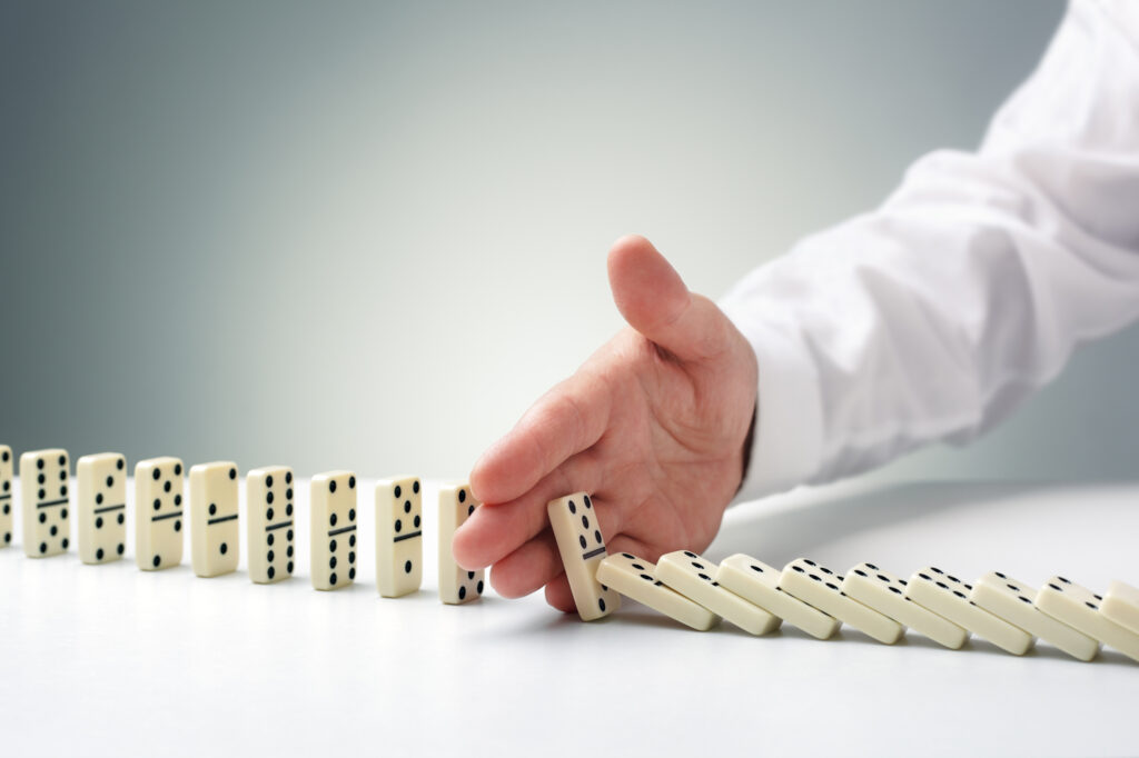 Stockphoto: hand is stopping a row of falling dominos
