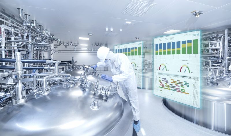 Pharmaceutical manufacturing environment with process equipment, plant personnel, and predictive INOSIM Foresight dashboards displaying production KPIs and operational planning insights.